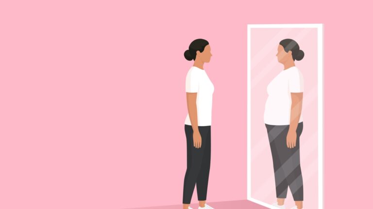 Woman looking at the mirror and seeing herself as overweight