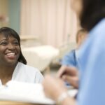 Female nurse talking to doctor at desk in hospital