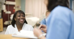 Female nurse talking to doctor at desk in hospital